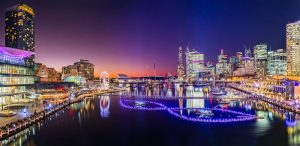 Darling Harbour at night during spring, with festival lights, ferris wheel, and Sydney city skyline.